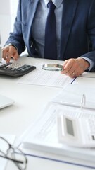 Business team analyzing financial documents, using calculators and laptop, working together on project in modern office. Audit and taxes concept