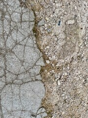 Detailed view of cracked concrete texture with gravel and soil background