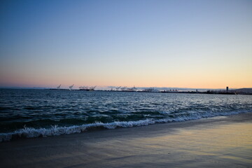 Tranquil sunset over Long Beach, California with soft waves, distant docks, and a glowing sky — capturing coastal serenity and the beauty of evening light.