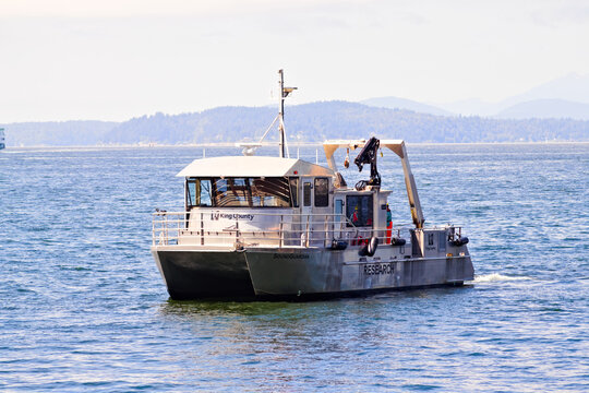 A sturdy research vessel glides across calm coastal waters, equipped with cranes and gear for scientific fieldwork, supporting marine studies, environmental monitoring, and data collection on the open