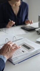 Close up of male accountant hands using calculator while collaborating with female colleague in office, calculating taxes and analyzing financial data. Audit and taxes concept