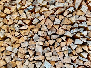 Pile of stacked chopped firewood pieces ready for storage and use in fireplace or stove