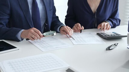 Chartered accountants analyzing financial reports with a magnifying glass and calculator for precise compliance verification. Audit and taxes in business - Powered by Adobe