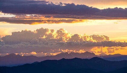 A dramatic sunset view over a mountain range, with vibrant golden clouds illuminating the peaks.