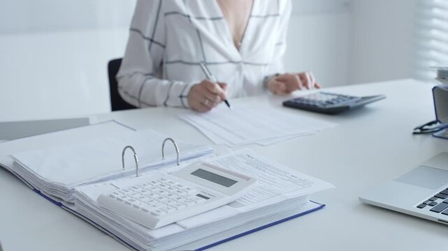 Close up of a calculator on financial documents, with an accountant taking notes, emphasizing accounting, finance, and tax preparation. Audit and taxes in business