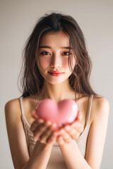 【縦写真】ハート型のオブジェを持つ女性