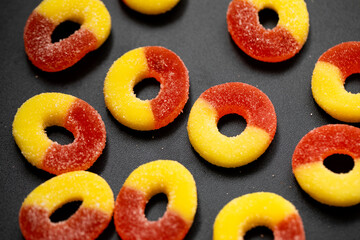 Closeup of Sugar Coated Peach Ring Gummies Candy on black background 