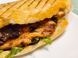Succulent grilled chicken sandwich with fresh lettuce and crispy bread on a white plate