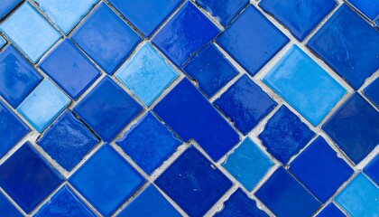 A close-up view of a wall adorned with various shades of blue square tiles, arranged in a diagonal pattern, creating a vibrant and captivating visual.