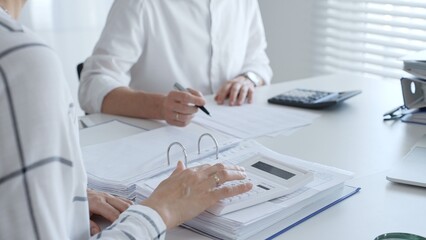 Two professional accountants colleagues are working together, using a magnifying glass and a...