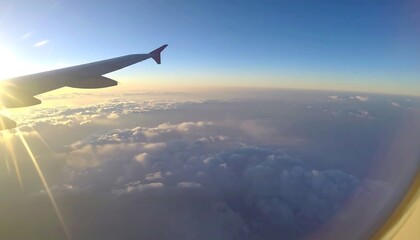 Fototapeta premium Airplane wing above a fluffy cloud layer, sun shining