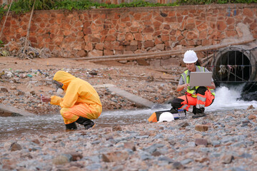 Environmental field team in protective gear analyzes water samples on a polluted beach. One holds a...