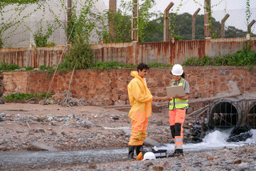 Environmental field team in protective gear analyzes water samples on a polluted beach. One holds a...