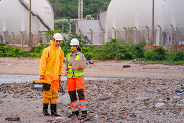 Environmental scientists conduct field assessment along a polluted coast, carrying lab tools and...