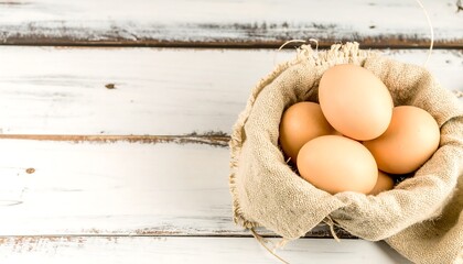 Fresh brown eggs nestled in a rustic burlap sack on a weathered white wooden surface.