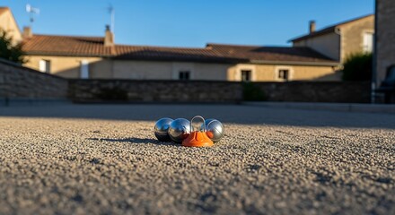 Naklejka premium Steel Boules and Orange Marker on a Gravel Pitch in Warm Sunlight