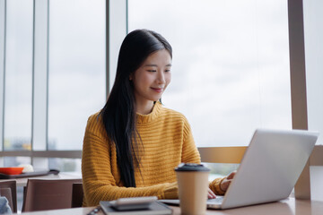 Young Asian Freelancer Working on Laptop in Modern Coworking Space