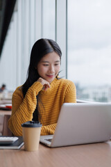 Young Asian Freelancer Working on Laptop in Cafe
