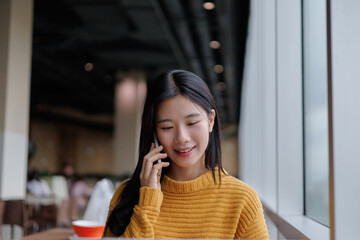 Young Asian Freelancer Working Remotely From Cafe and Talking on Phone