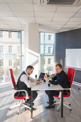 Two Caucasian men using smartphones while sitting at a desk. 