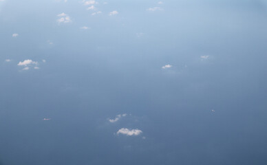 Sky above the clouds, view from a window plane, with a large ship passing by.