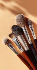 Makeup brushes arranged on a beige background, showcasing various shapes and finishes