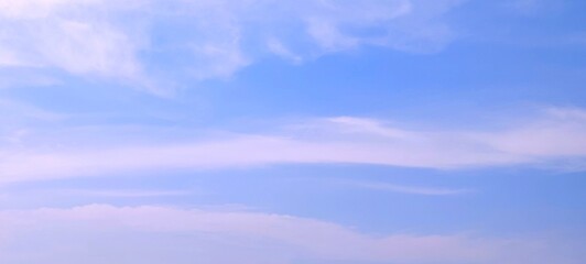 Panorama view of bright blue sky with fluffy white clouds on a clear sunny day. Sky panorama clear blue with white clouds in spring. Cloudscape. Clear blue sky, bright spring, wallpaper landscape.