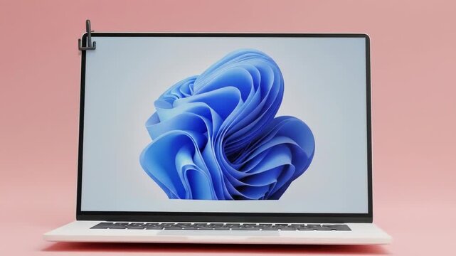 A laptop computer with a light-blue abstract design on the screen, set against a pale-pink background