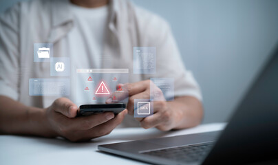 Businessman using smartphone and laptop with digital warning alert, representing cybersecurity risk, data protection, system error and online security issues in modern technology