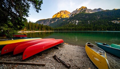 Colorful canoes rest on a pebble shore, bathed in morning light, as serene mountains rise above a tranquil lake.
