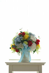 The colorful fake flower vase is located on a white table