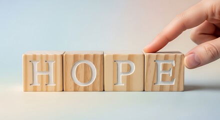 A hand gently touches a wooden block spelling out the word hope, creating a peaceful and reassuring image.