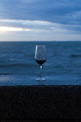 A single glass of chilled white wine on a table by the blue ocean and beach