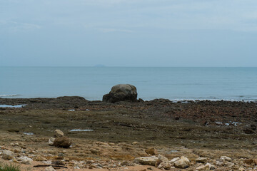 Sheep grazing on a rocky coastline with waves from the blue sea crashing on the shore