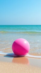 Naklejka premium Pink ball on a sandy beach with gentle waves ocean