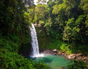 Lush jungle waterfall cascades into a vibrant turquoise pool surrounded by dense greenery.