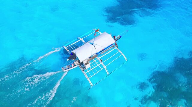 Fly high above the azure waters of Balabac, Palawan, showcasing the tropical beach, island landscapes, and clear waters as a boat sails gracefully through this tropical paradise.