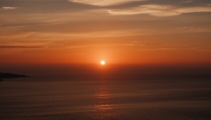 Obraz premium Golden sunset over the ocean with light reflecting on the water and hazy orange sky above horizon