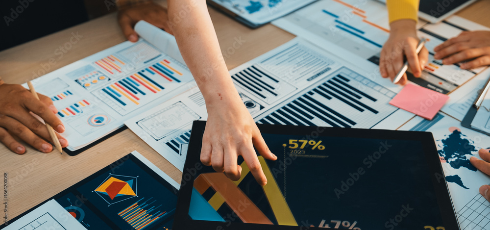 Poster a collaborative business meeting scene where diverse professionals analyze charts and graphs on a ta