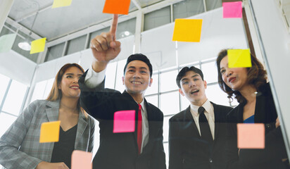 group of people are looking at  wall covered in colorful sticky notes