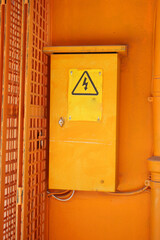 Yellow electrical control box on bright orange wall