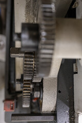 Close-up of gears on the covered external part of a lathe machine.
