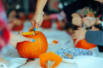 People Carving Pumpkins at a Halloween Party. Adults and kids working together in autumn decoration...