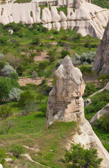 View on conical historic cave dwelling among green mountain valley in Uchisar at Nevsehir Province in Cappadocia, Turkey. The house is carved into a rock formation. Amazing Volcanic rock formations