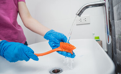 Young housewife diligently scrubs and cleans the sink in bathroom
