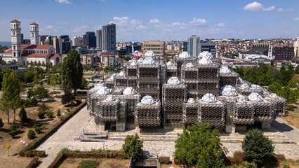 Drone view of the modern Kosovo National Library with the Pristina skyline in the background