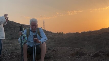 Happy senior couple in their seventies hiking together in a desert landscape during active vacation weekend, outdoor physical activity, trekking, healthy lifestyle, walking adventure and nature explor - Powered by Adobe