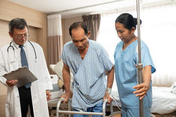 Asian doctor helps an elderly man use a walker mobility support at hospital
