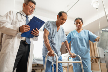 Asian doctor helps an elderly man use a walker mobility support at hospital