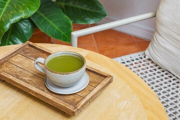 a cup of hot pure matcha on wooden plate and table in cafe